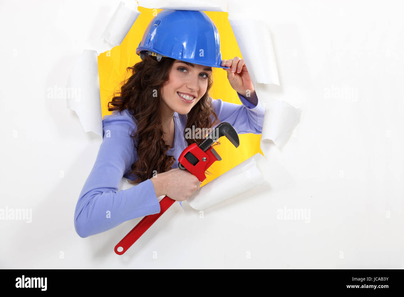 female worker watching us through a hole in a paper wall Stock Photo