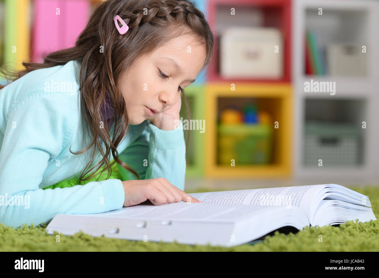 Little girl lying on floor and reading book Stock Photo - Alamy