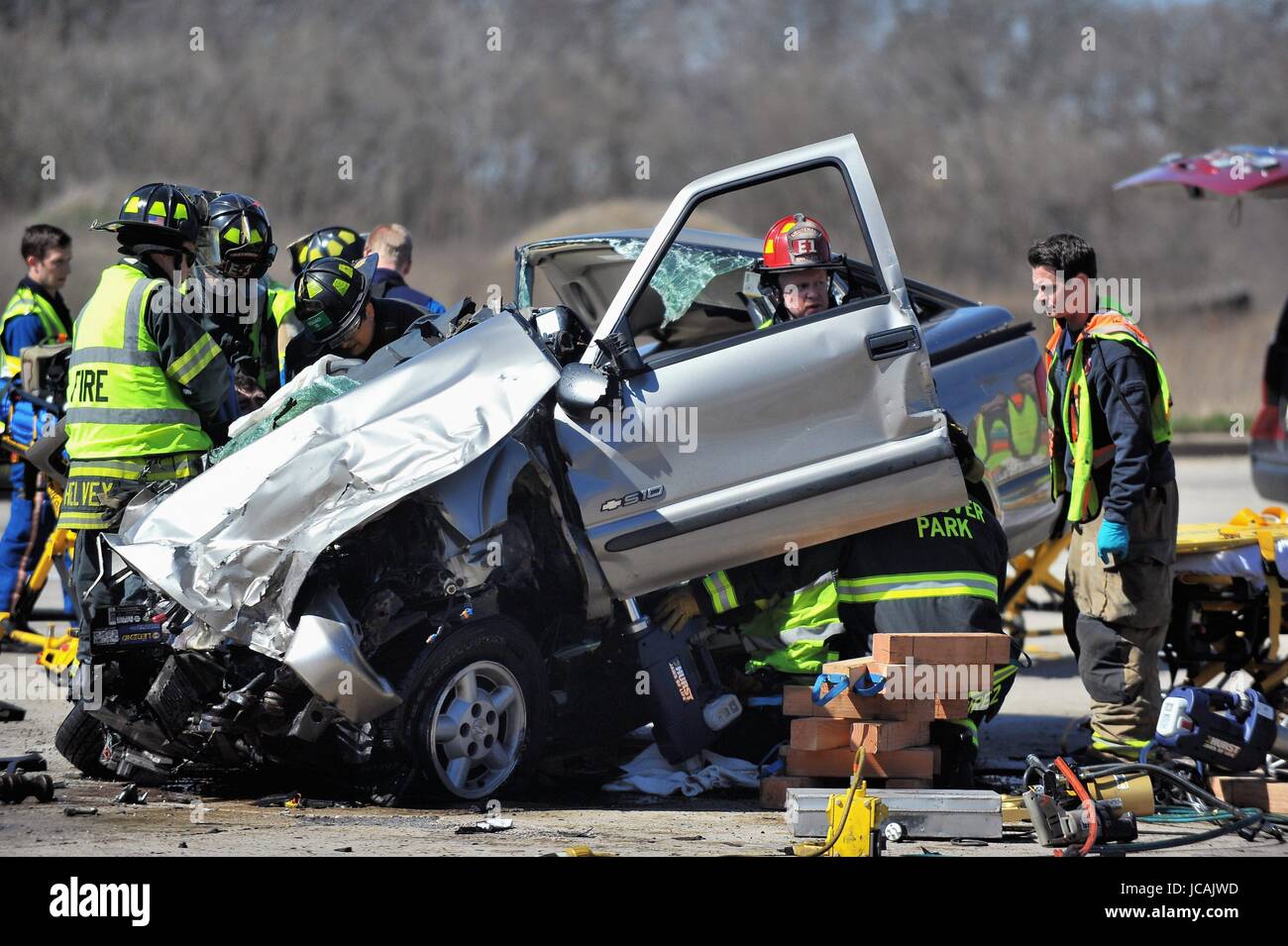 The residue of a serious, high speed car crash is surveyed by firefighters and paramedics as they worked to extricate a victim from the debris. USA. Stock Photo