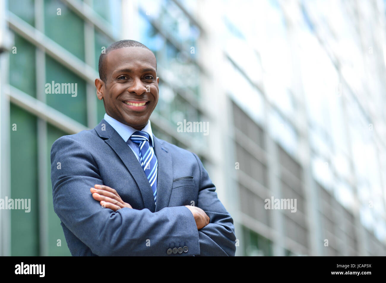 Businessman standing with arms crossed near office building Stock Photo ...