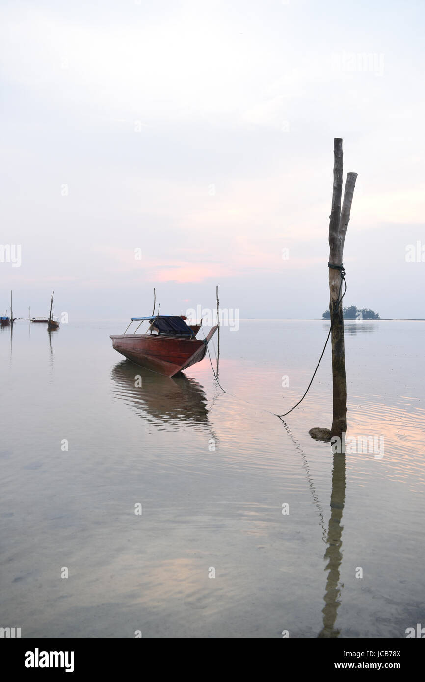 Fishing boat near the beach bound to a wood stick on the sea with light  sunset background taken in Batam in Indonesia Stock Photo - Alamy