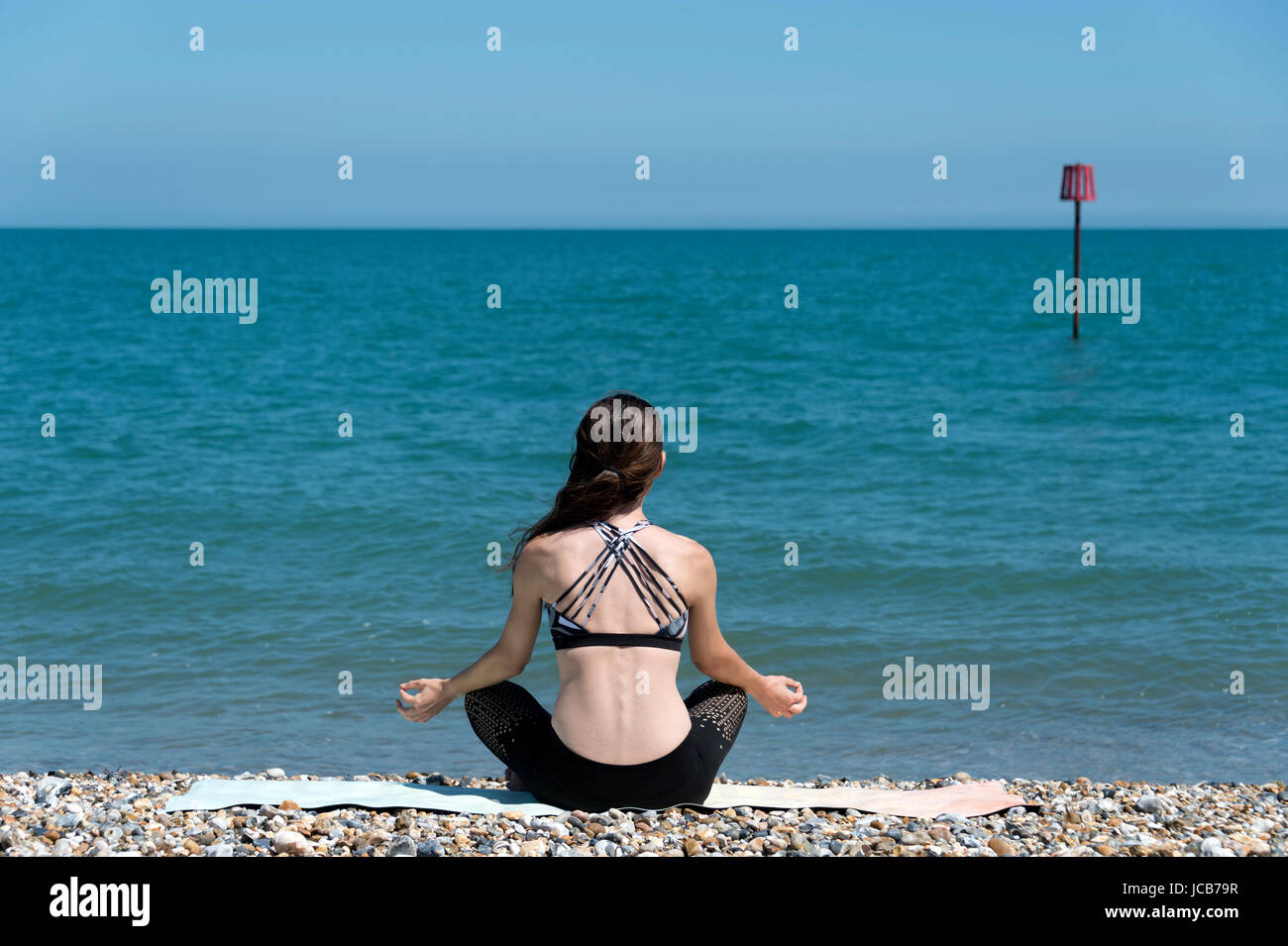 woman sitting on the beach meditating. Stock Photo