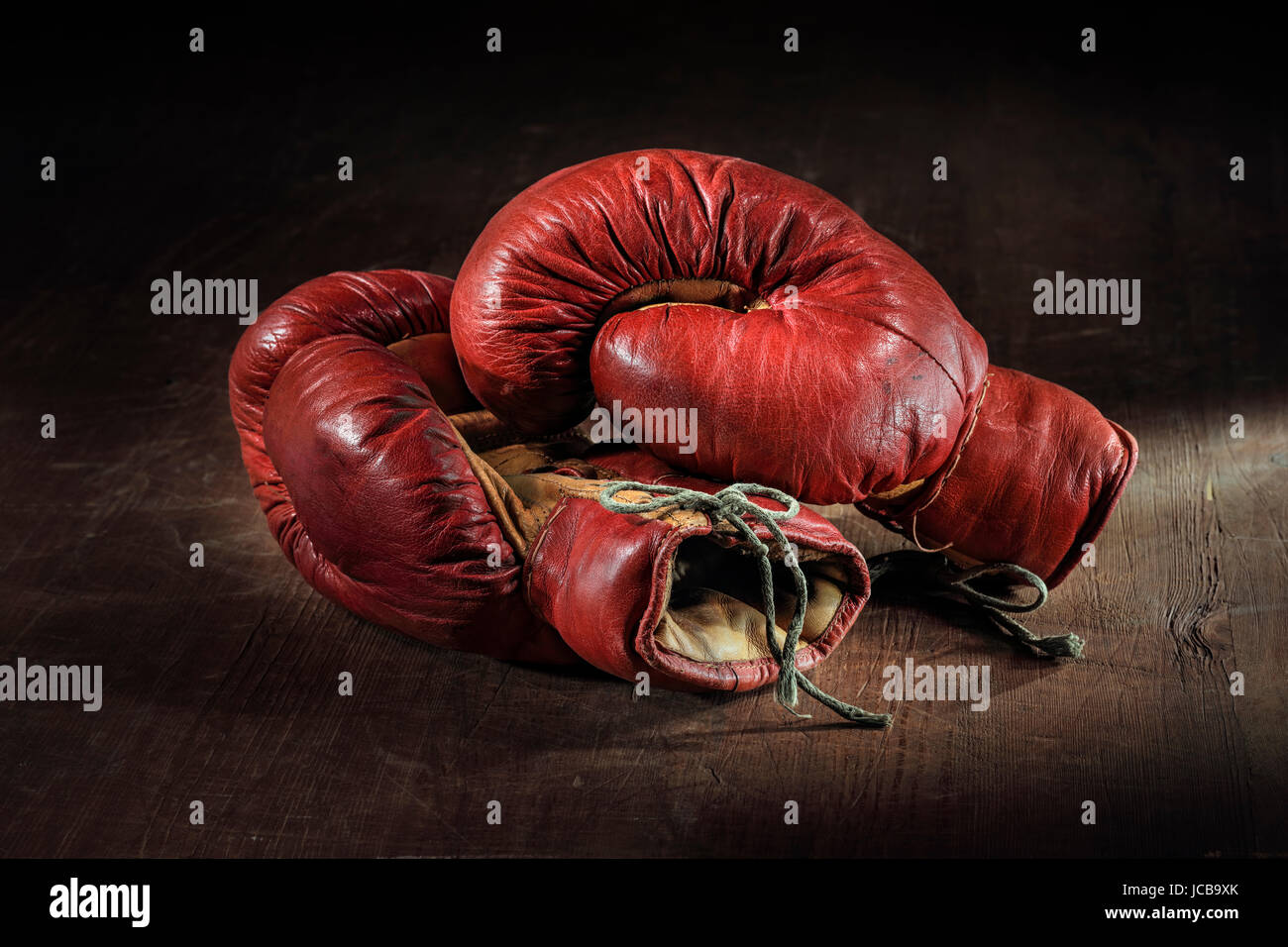Old red boxing gloves on wooden background. Stock Photo