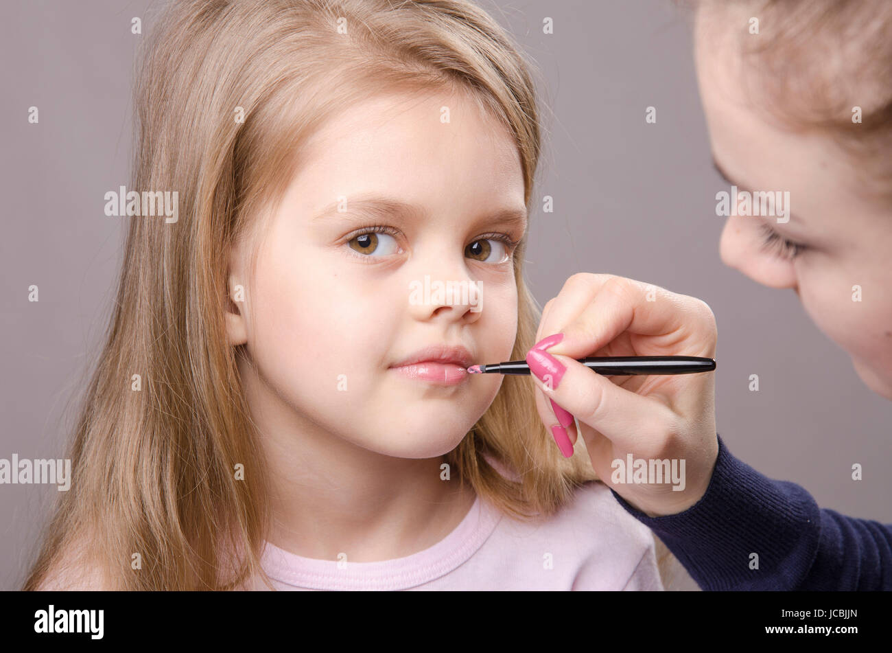 Makeup artist in the process of makeup lipstick five year old girl ...