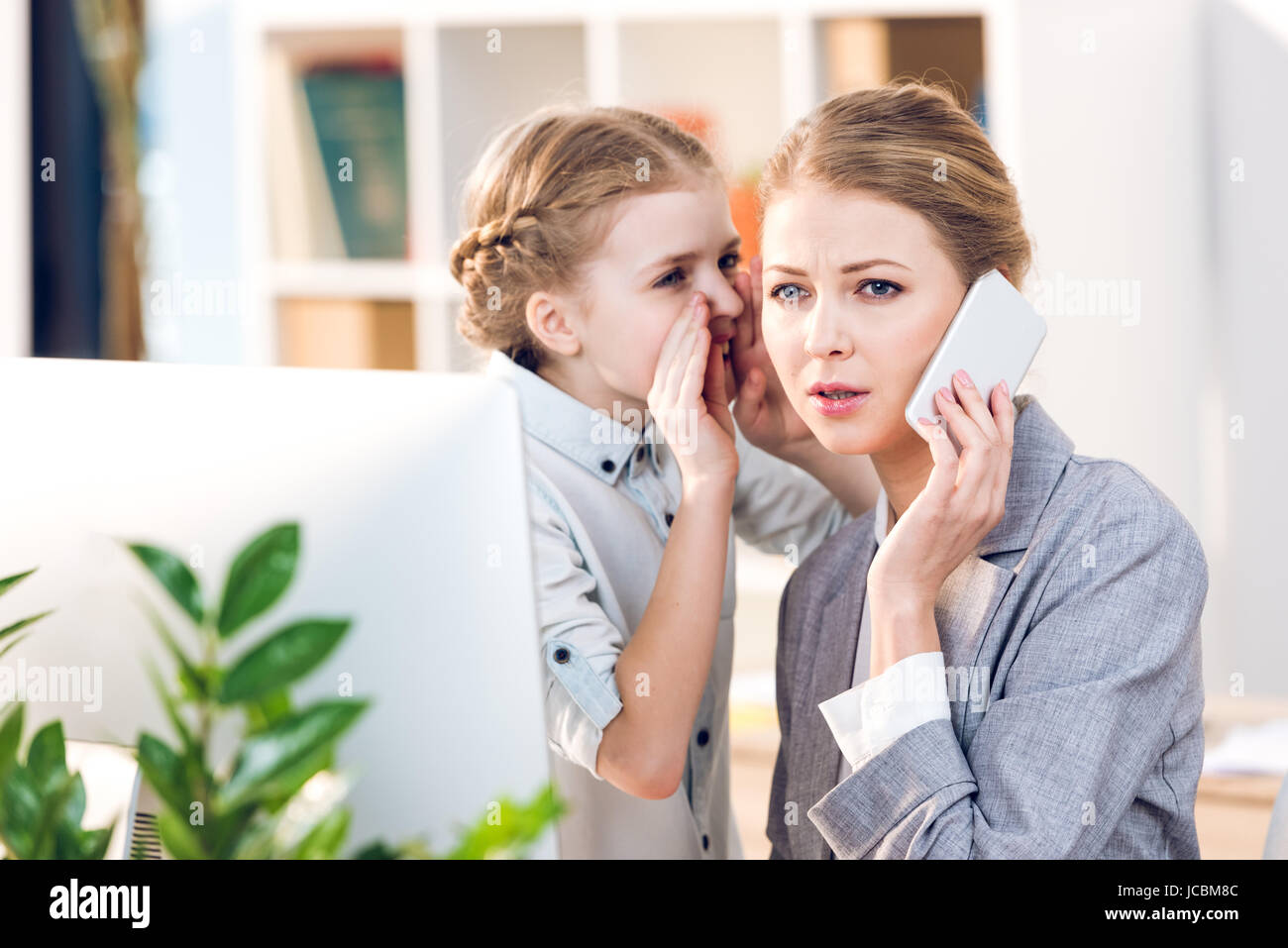 young mother and daughter talking in business office, businesswoman using smartphone Stock Photo