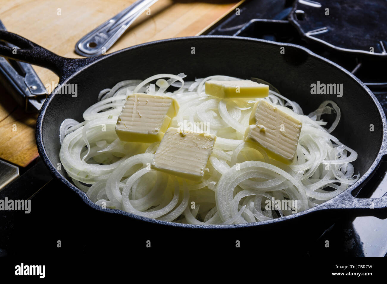 Onions cooking with butter in cast iron skillet Stock Photo Alamy