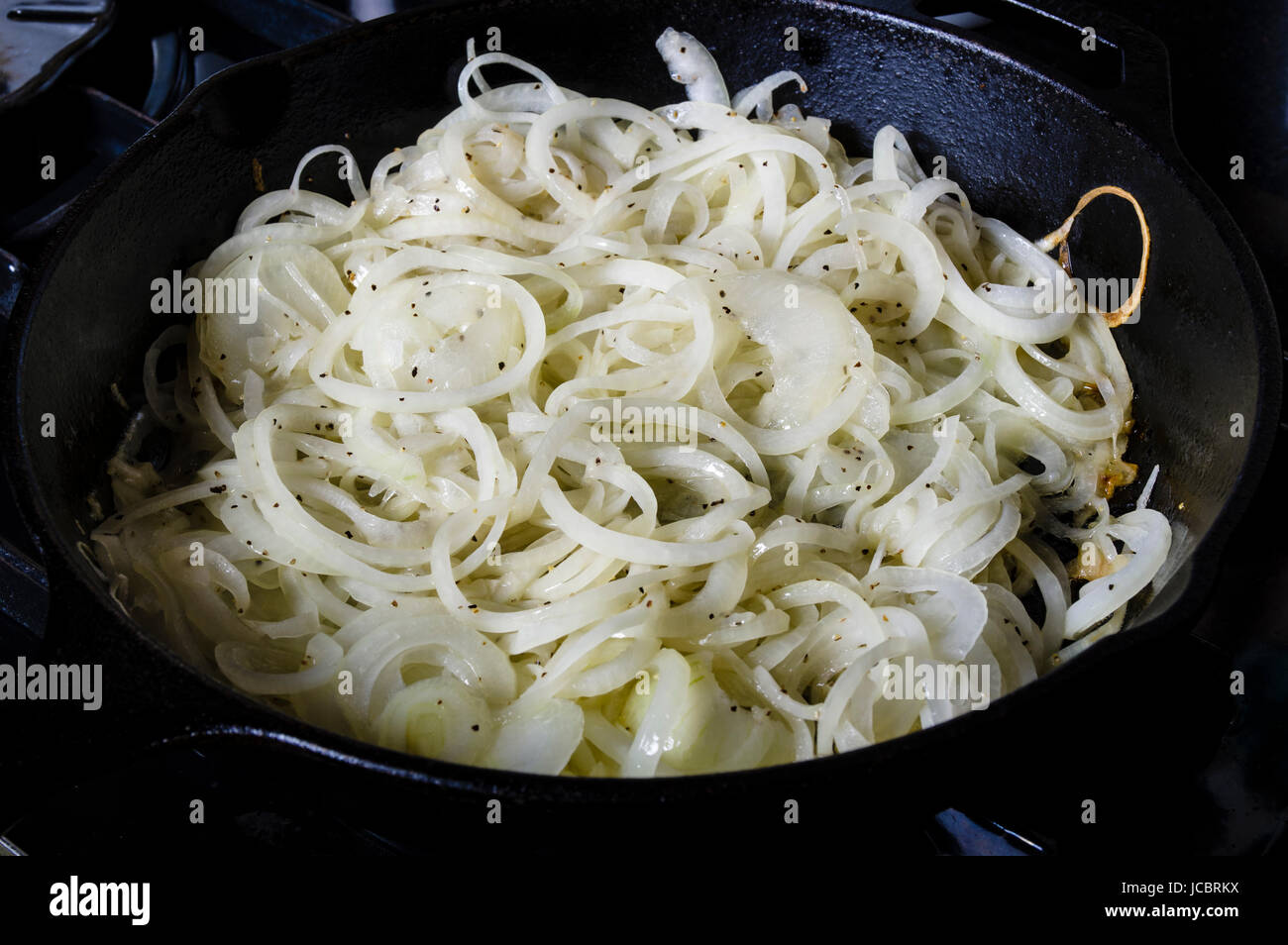 Onions carmaelizing in cast iron skillet on the stove Stock Photo Alamy