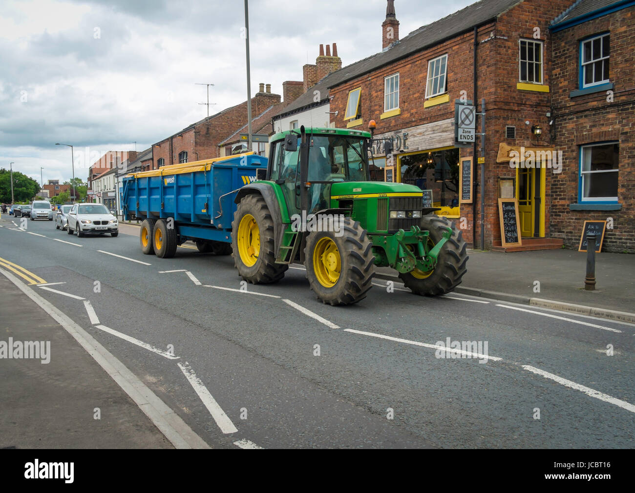 A John Deere model6910 farm tractor pulling a large trailer in the centre of a Yorkshire Market Town Stock Photo