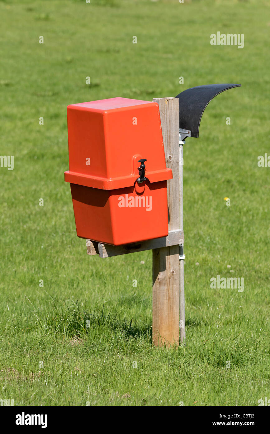 Red box containing a fire extinguisher and a rubber mat on a pole for fire fighting in a camping field. Dorset England UK June 2017 Stock Photo