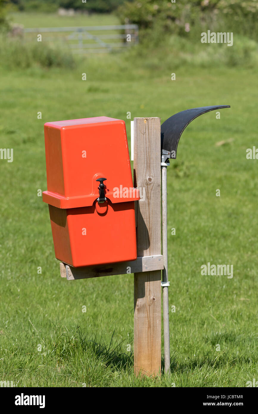 Red box containing a fire extinguisher and a rubber mat on a pole for fire fighting in a camping field. Dorset England UK June 2017 Stock Photo