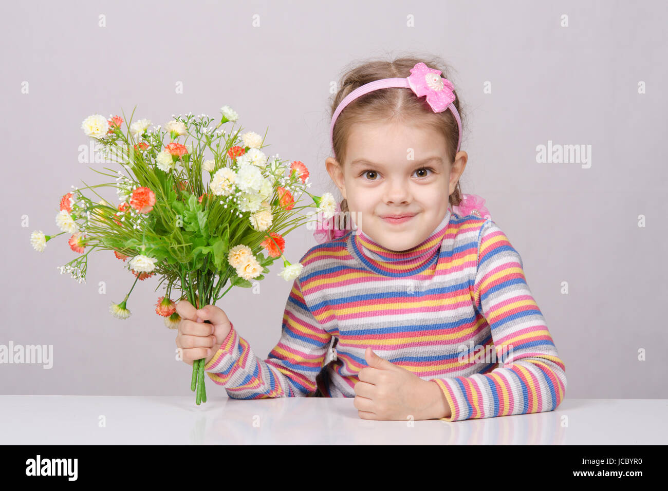 Girl with a bouquet of artificial flowers sitting at the table Stock ...