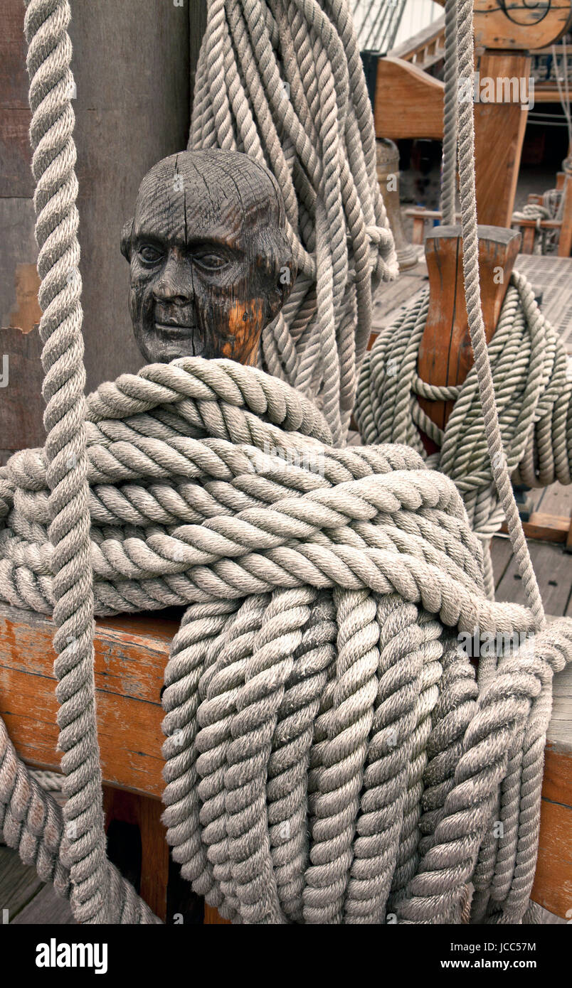 Ropes around a head shaped wooden cleat on an old vessel Stock Photo