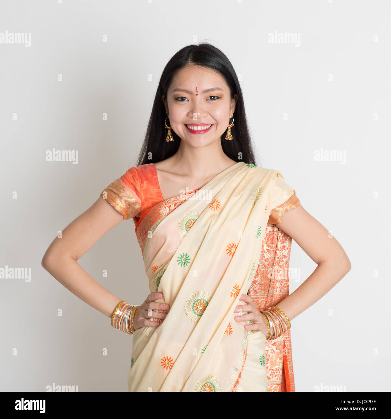 Portrait of confident Indian girl in sari smiling over grey background ...