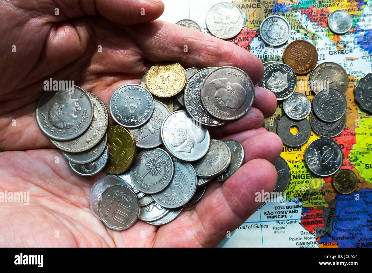 Hands Holding Multiple International Coins Stock Photo