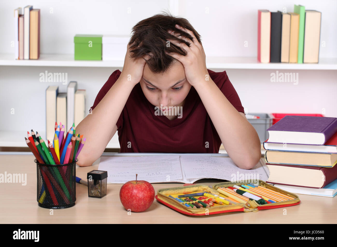 Ein junger Schüler verzweifelt bei den Hausaufgaben in der Schule Stock Photo