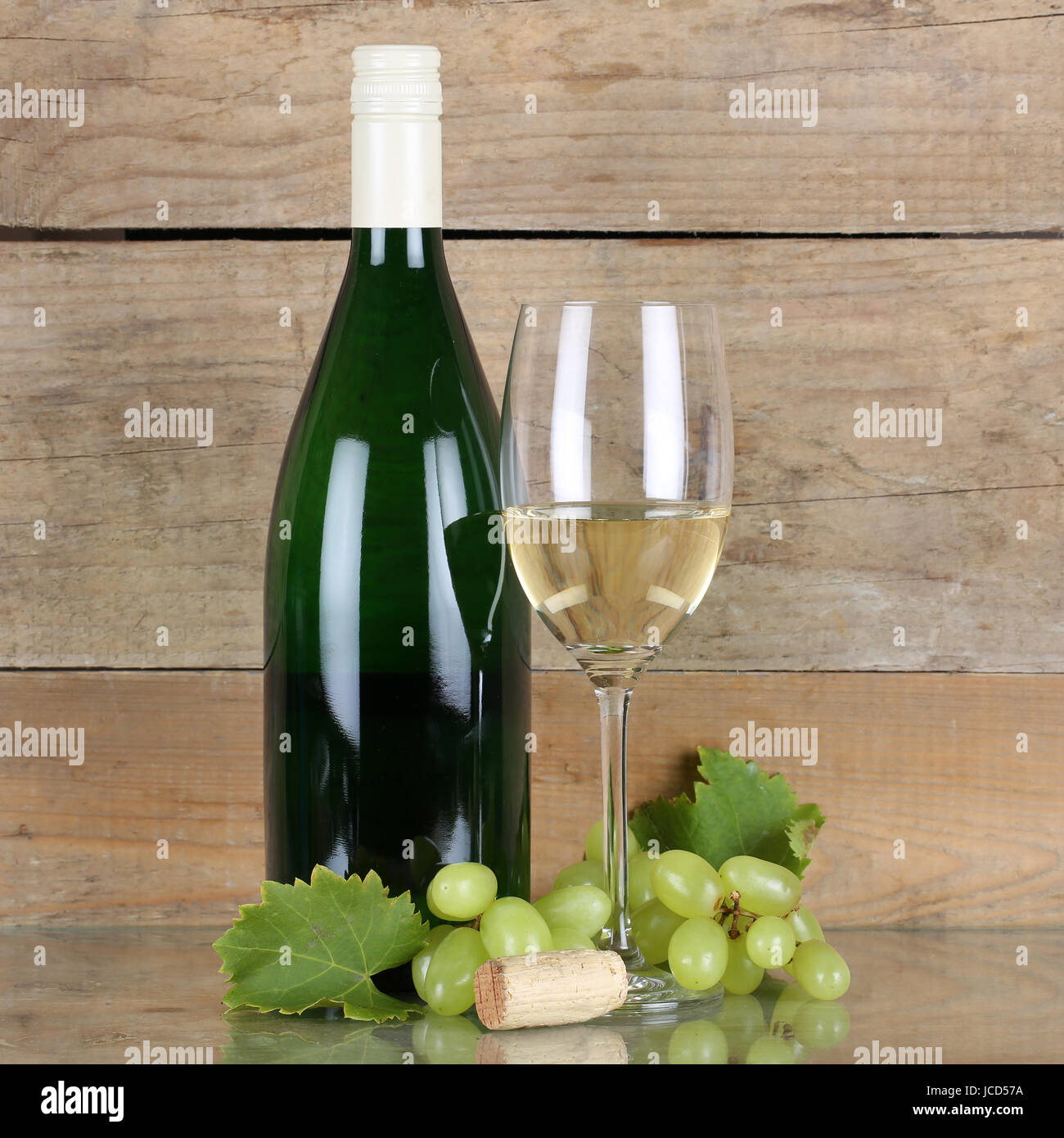 Weißwein in Weinflasche und Weinglas vor Holz Stock Photo