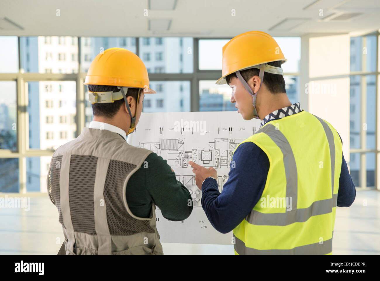 Back of two architects with design drawing talking Stock Photo