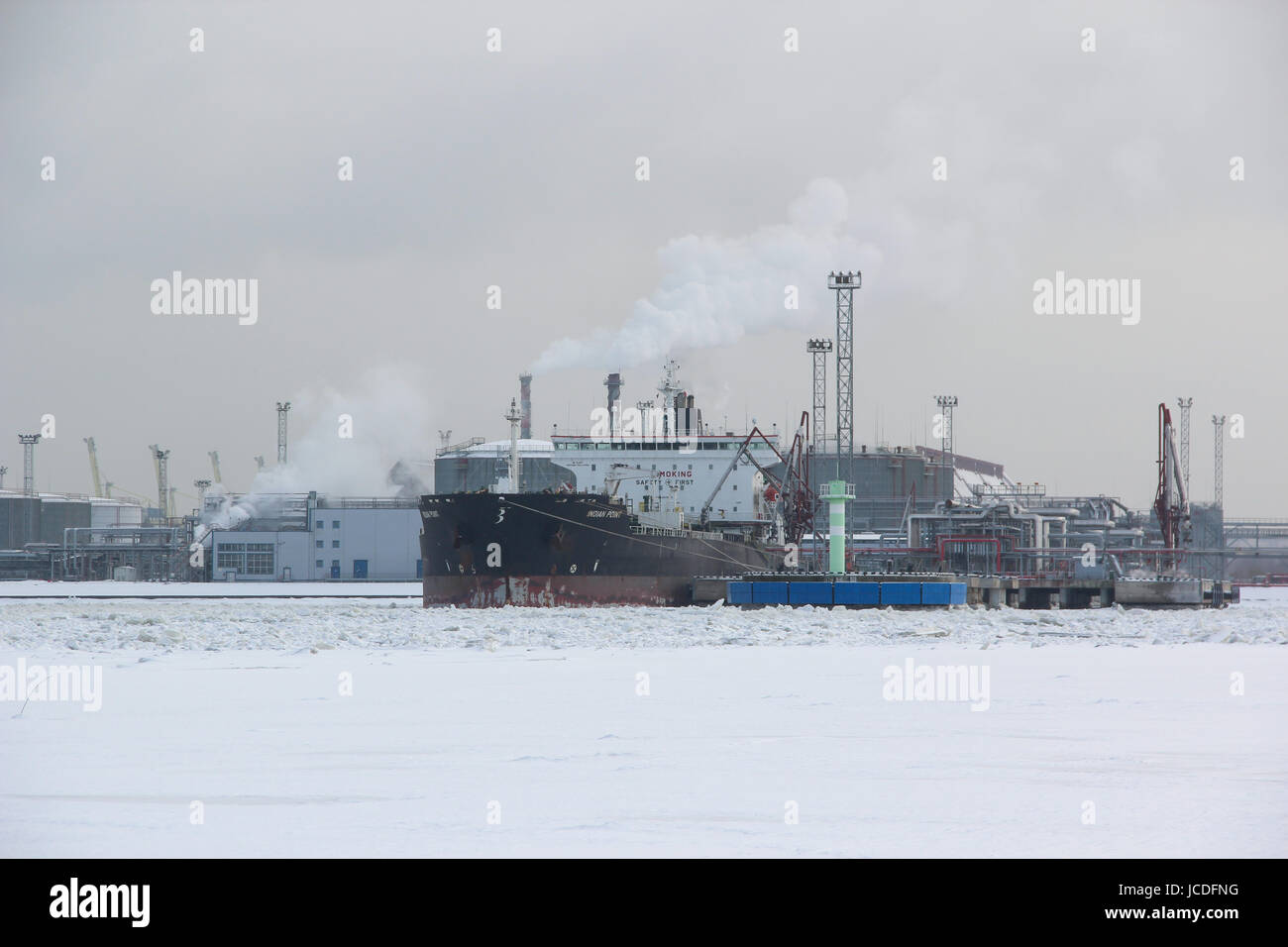 Oil Chemical Tanker 'INDIAN POINT' at the harbor. The ship refuels petroleum in the frozen snow-covered port city. Water was cold, ice floes punched Stock Photo