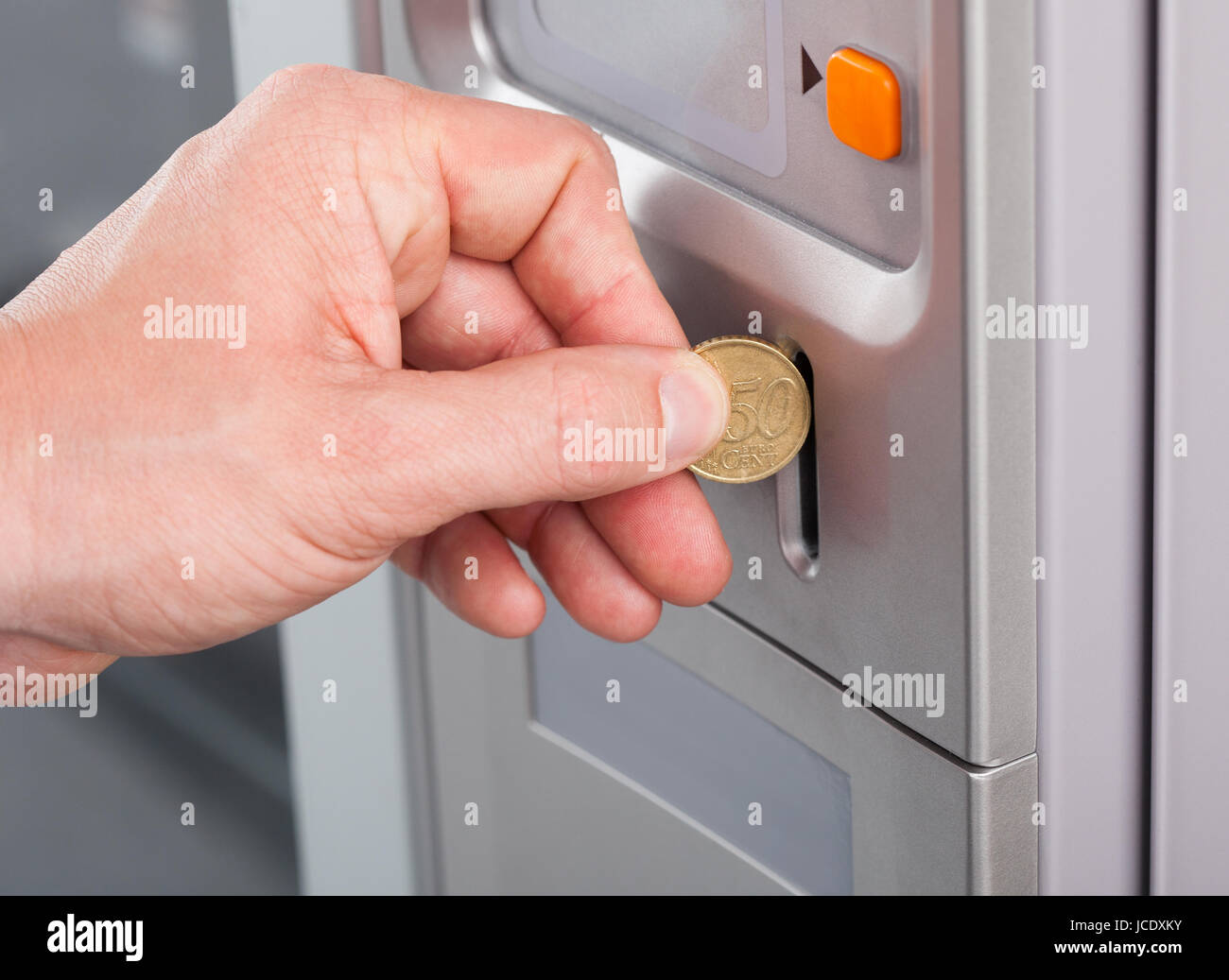 Close-up of human hand inserting coin in vending machine Stock Photo