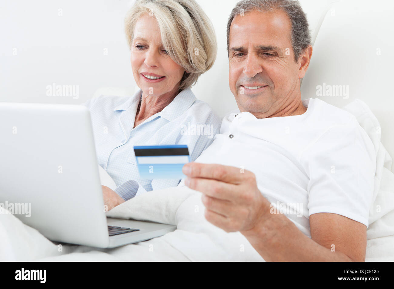 Couple In Bedroom Shopping Online Holding Credit Card Stock Photo Alamy