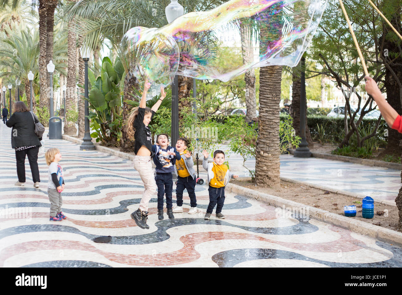 Children playing with bubbles on the street in Alicante, Spain. Stock Photo