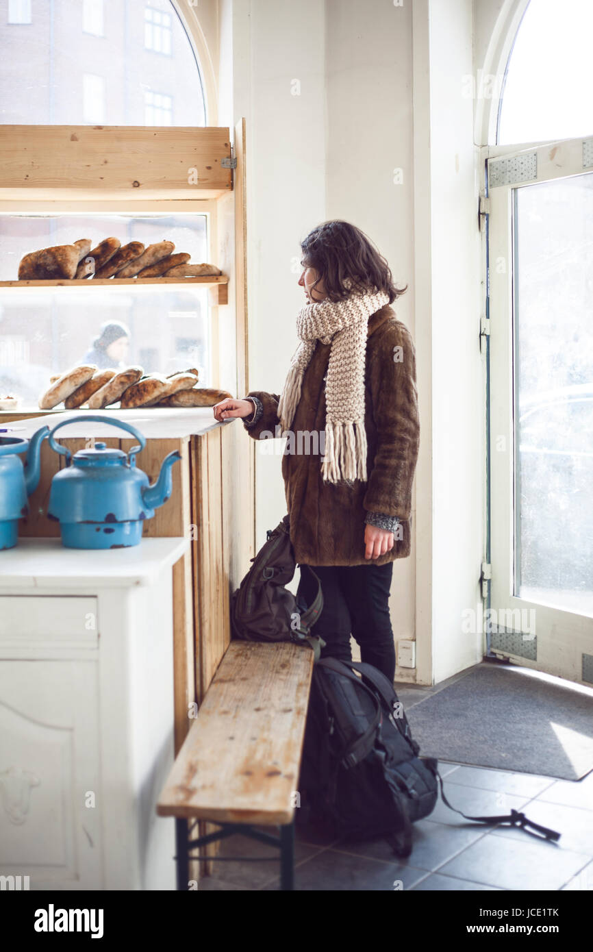 A candid photograph of a backpacker ordering artisan bread in a backstreet bakery in Copenhagen. Stock Photo
