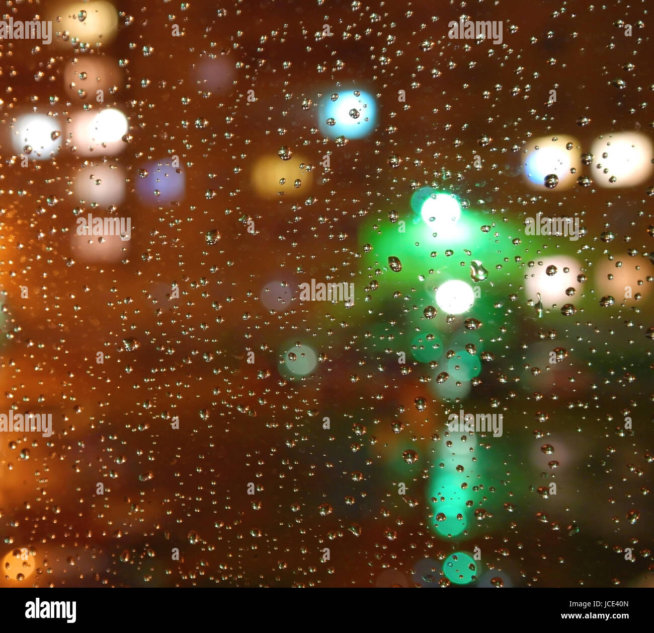 Drops of rain on window, night. On back plan washed away lights of the torches. Shallow DOF Stock Photo