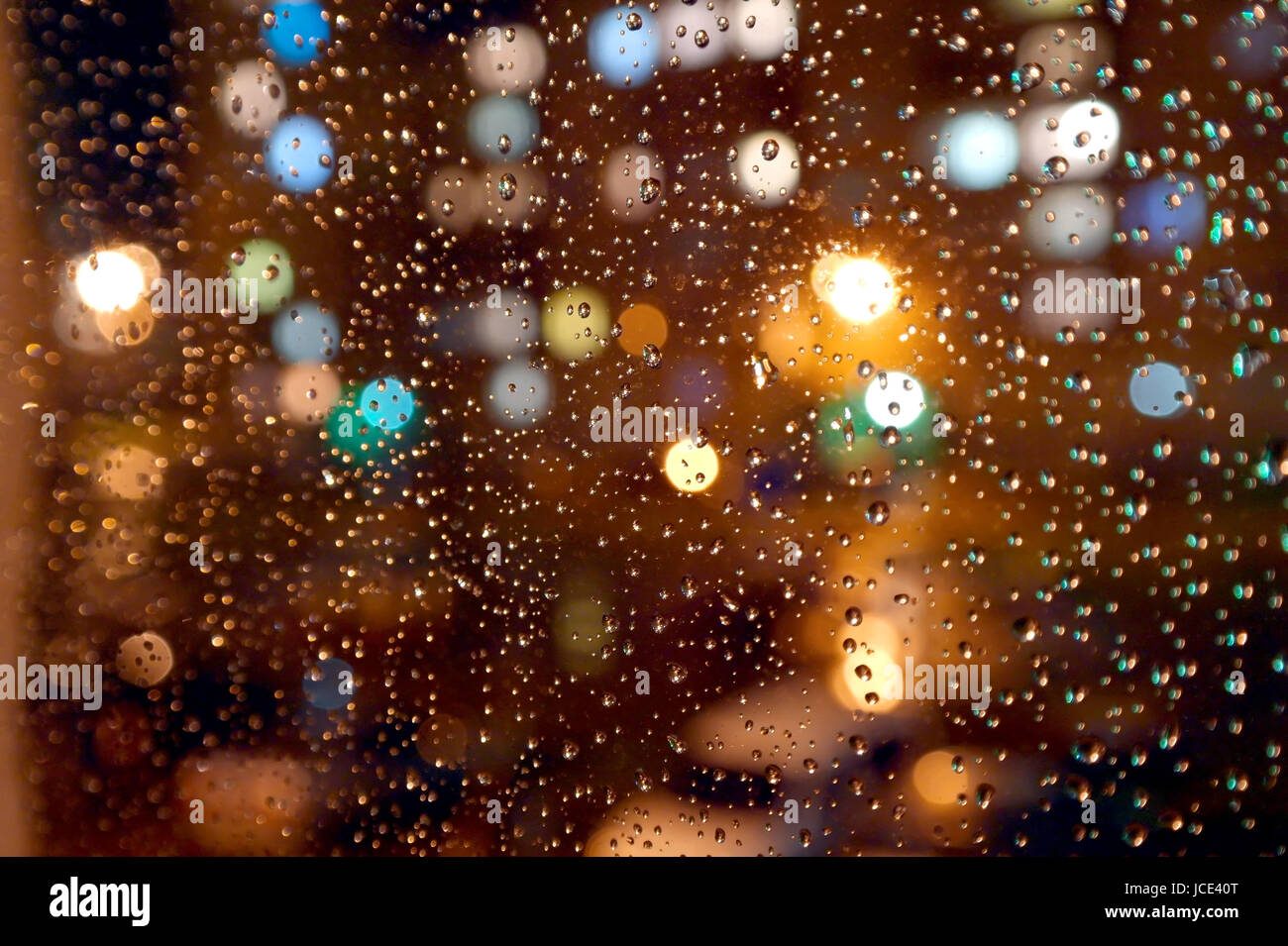 Drops of night rain on window, on back plan washed away lights of the torches. Shallow DOF Stock Photo