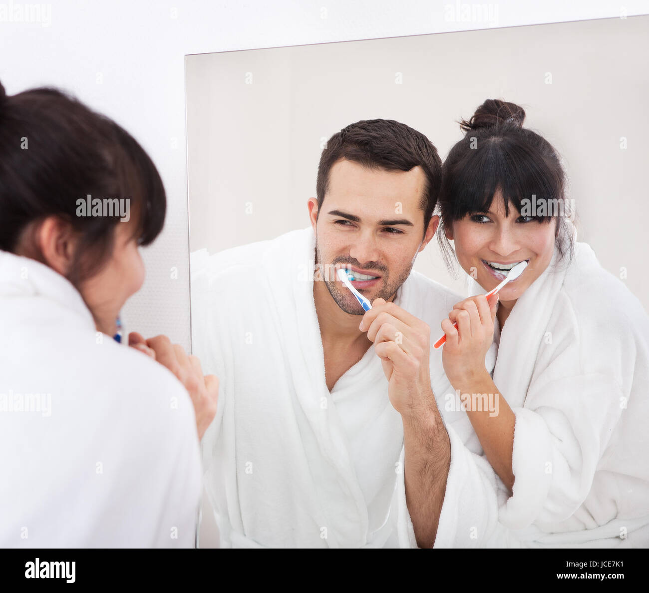 Young couple brushing teeth together at home in the bathroom Stock