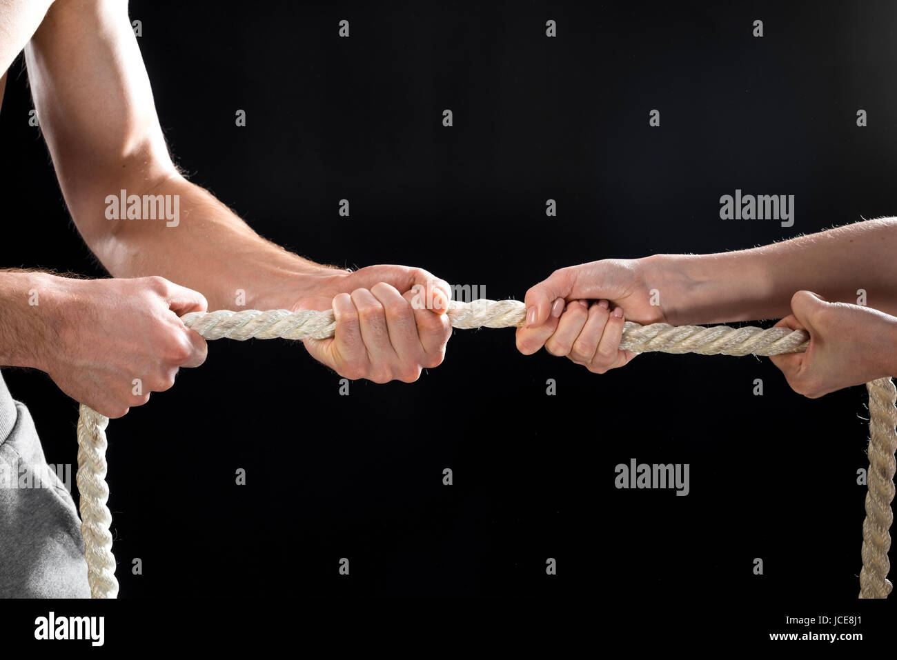 cropped view of man and woman pulling rope isolated on black Stock ...
