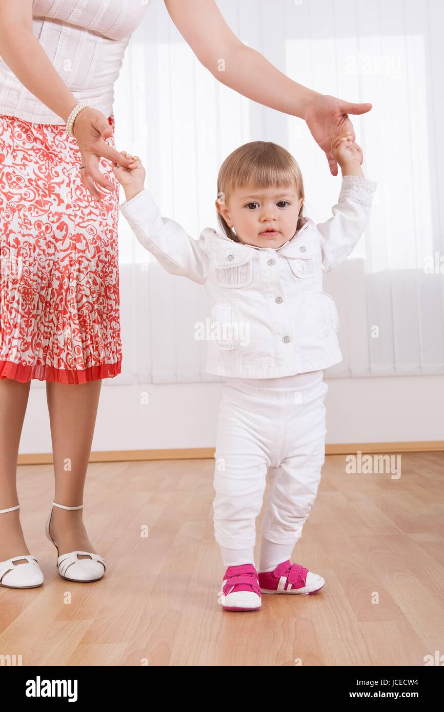 Mother helping baby daughter walk hi-res stock photography and images ...