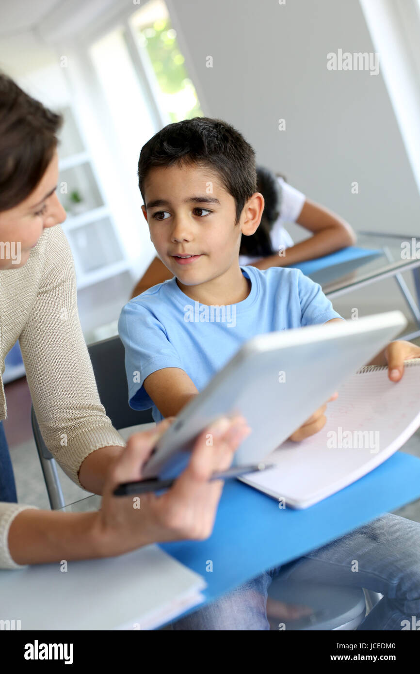 Teacher and schoolboy using electronic tablet in class Stock Photo - Alamy