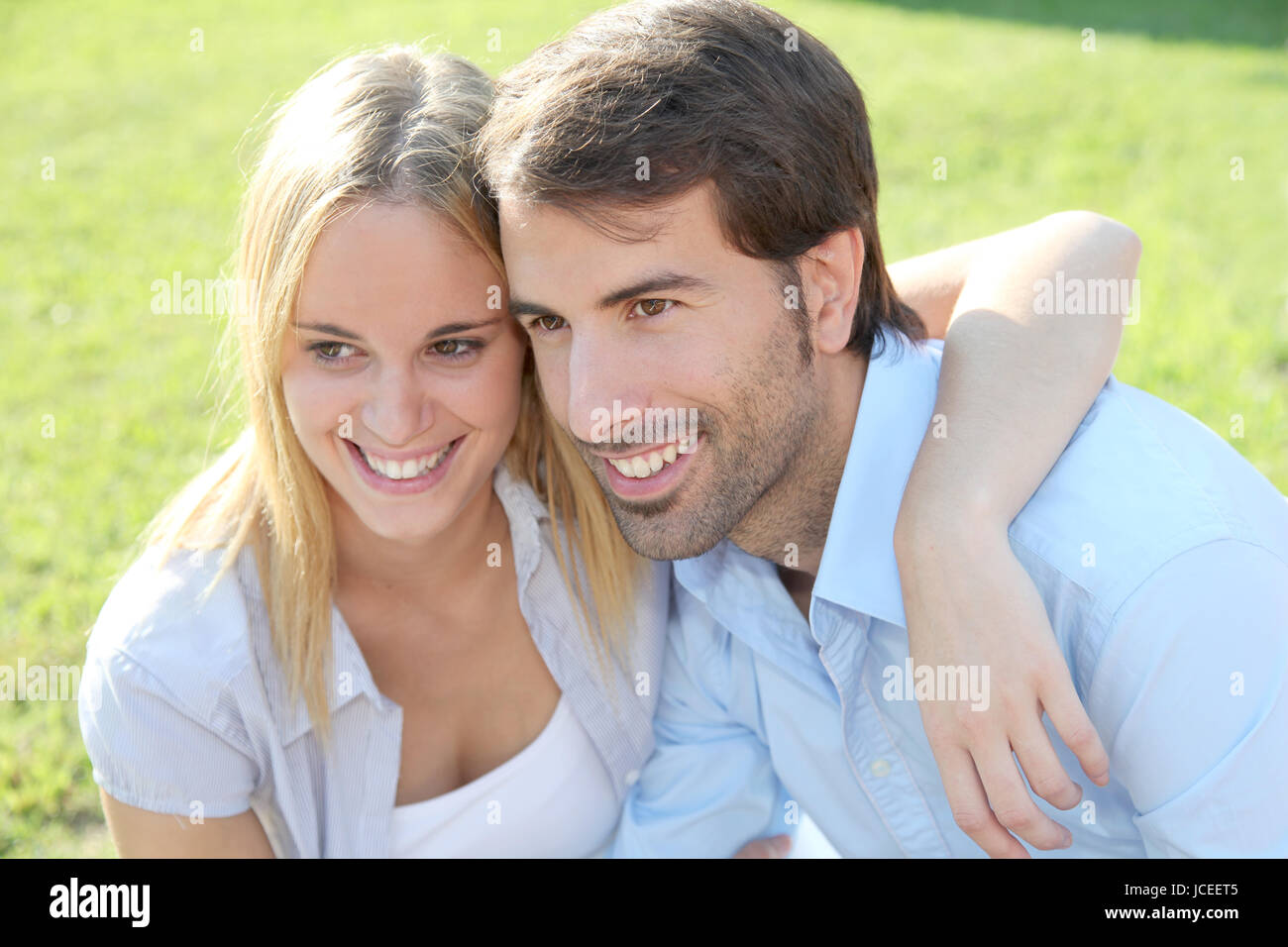 Happy young couple sitting in yard Stock Photo - Alamy