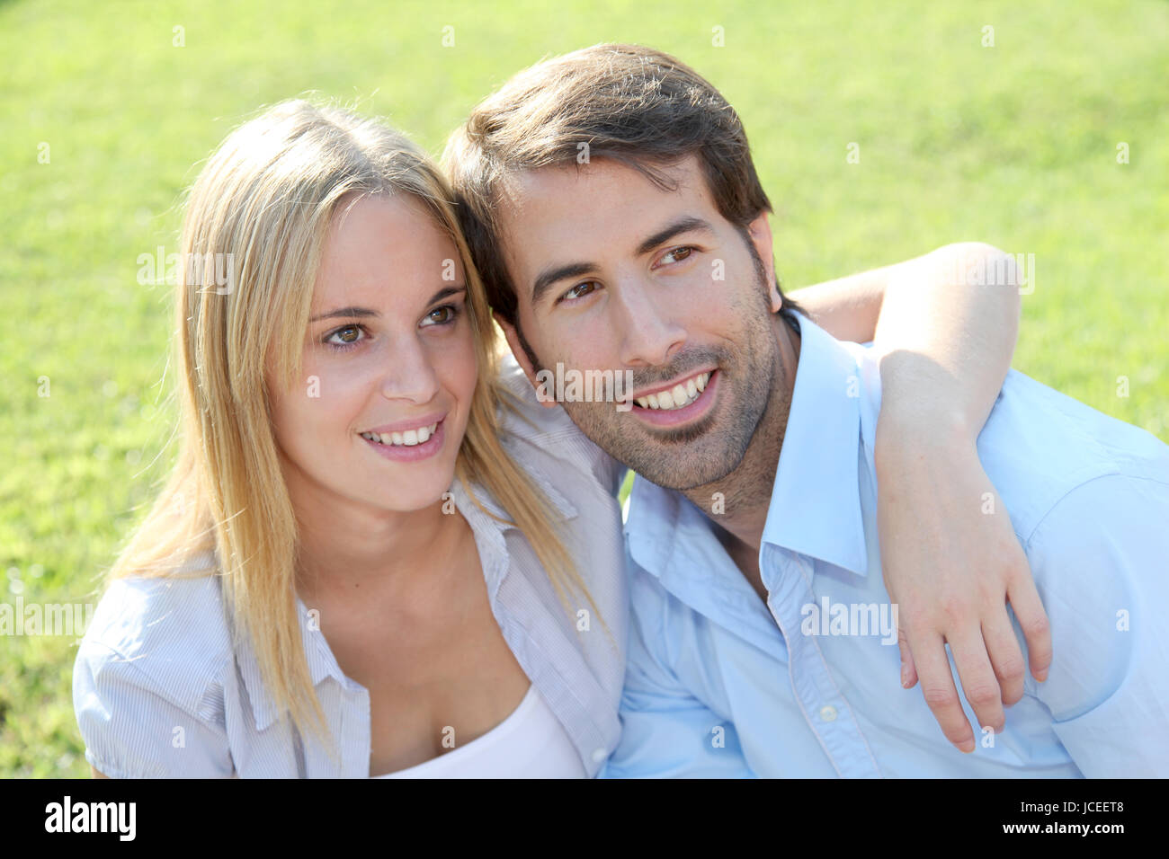 Happy young couple sitting in yard Stock Photo - Alamy