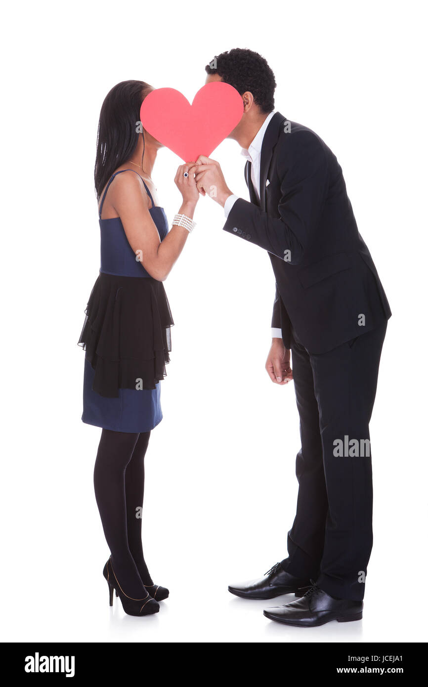 Portrait Of Couple Kissing Behind A Paper Heart Over White Background ...