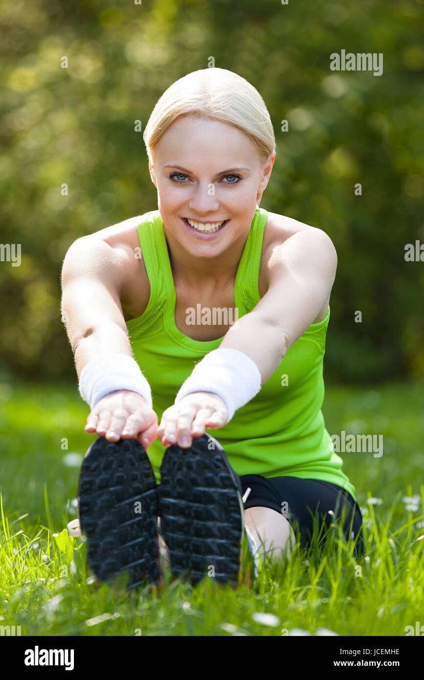 Fit blonde stretching on grass hi-res stock photography and images - Alamy