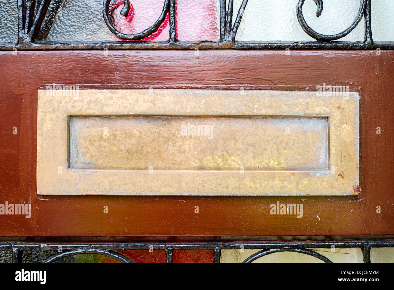 Tarnished Brass Letterbox On Doorframe Surround To Domestic