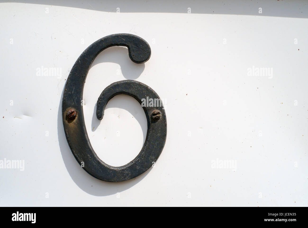 Black number '6' mounted to white background on front of house. Stock Photo