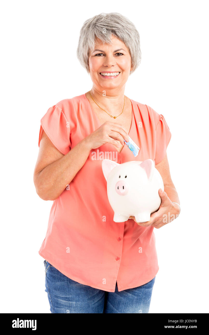 Portrait of a happy old woman putting money on a piggy bank, isolated ...