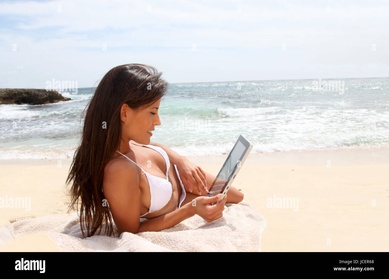 Beautiful woman in bikini using tablet on the beach Stock Photo Alamy