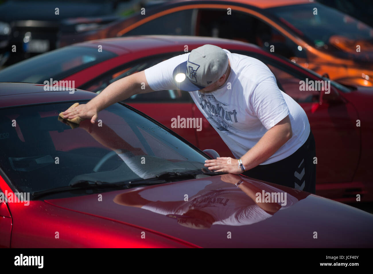 Daniel Heine from Frankfurt polishes his Opel Calibra from the year 1994  during the Opel Meeting in Oschersleben, Germany, 15 June 2017. The varnish  of the car is a candy gloss called "