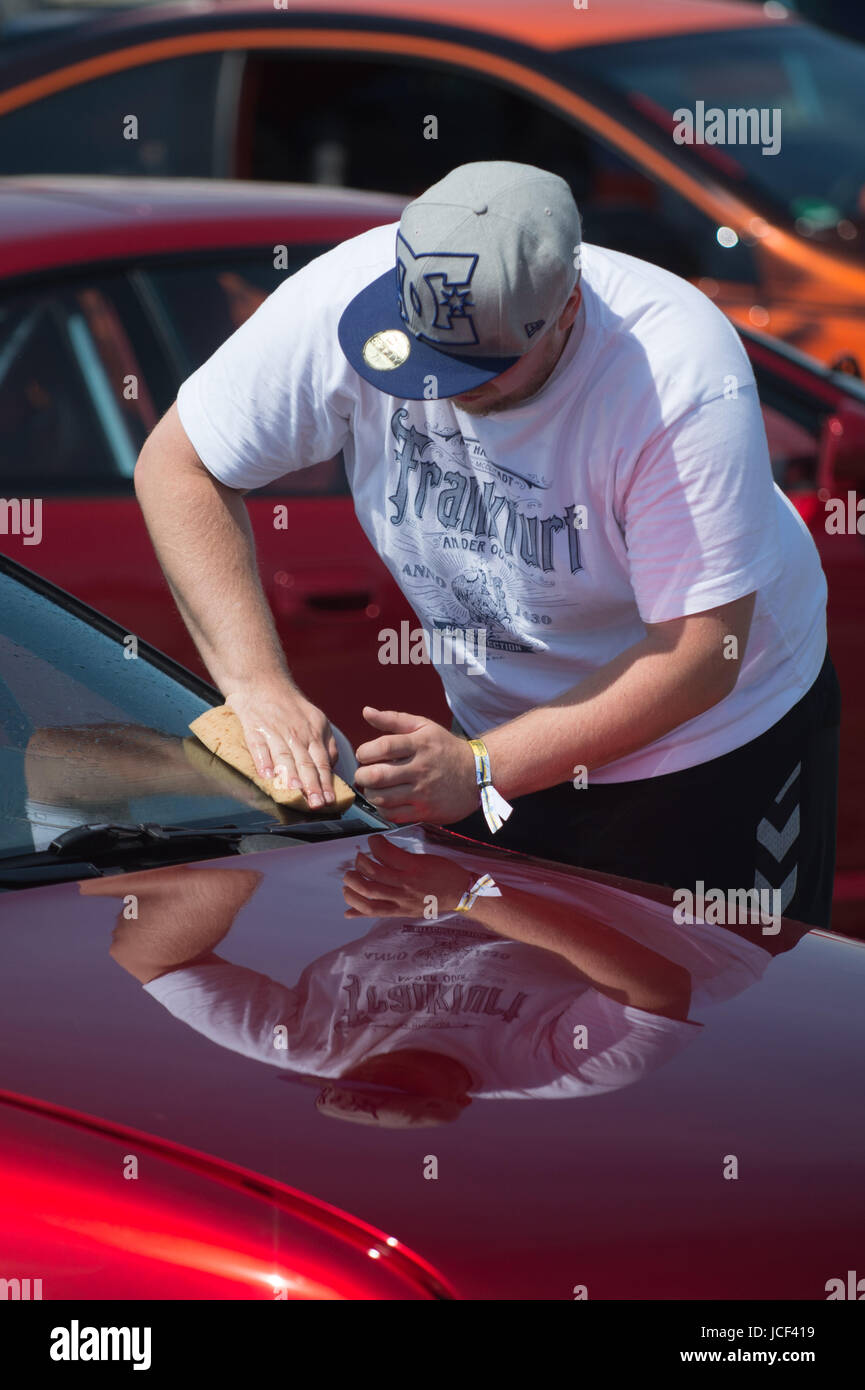 Daniel Heine from Frankfurt polishes his Opel Calibra from the year 1994 during the Opel Meeting in Oschersleben, Germany, 15 June 2017. The varnish of the car is a candy gloss called 'Apple Red'. The Opel Meeting is taking place for the 22nd time and will last until the 18th of June 2017. Photo: Klaus-Dietmar Gabbert/dpa-Zentralbild/ZB Stock Photo
