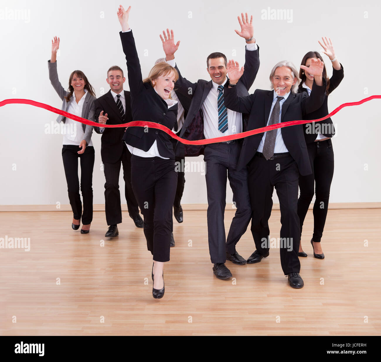 Jubilant business people celebrating raising their arms in the air and ...