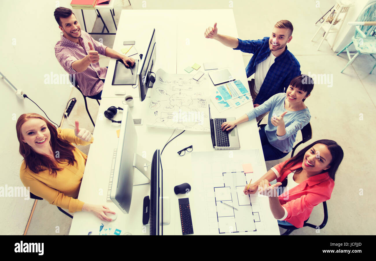 creative team with computers showing thumbs up Stock Photo - Alamy