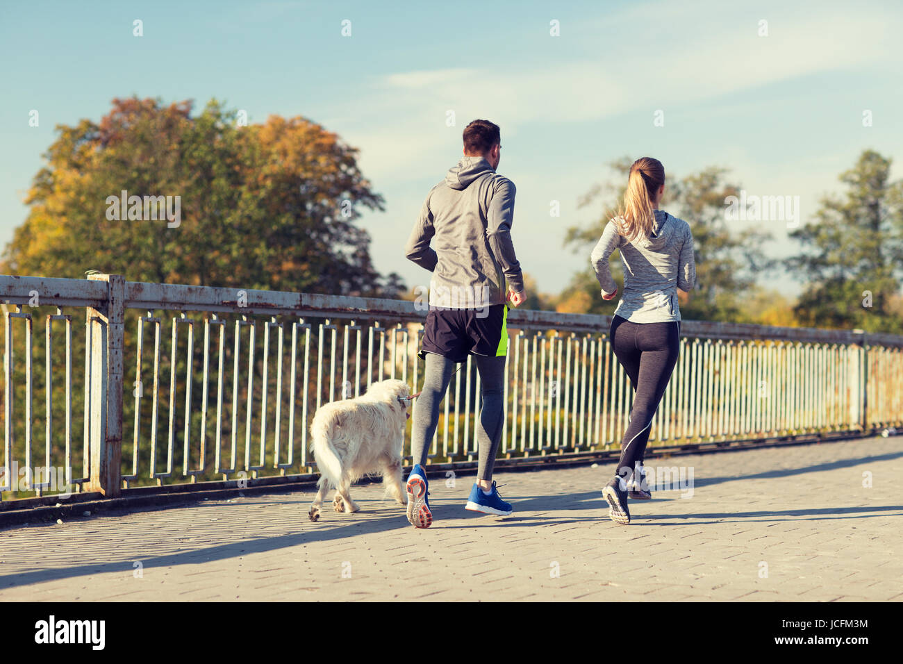 couple with dog running outdoors Stock Photo