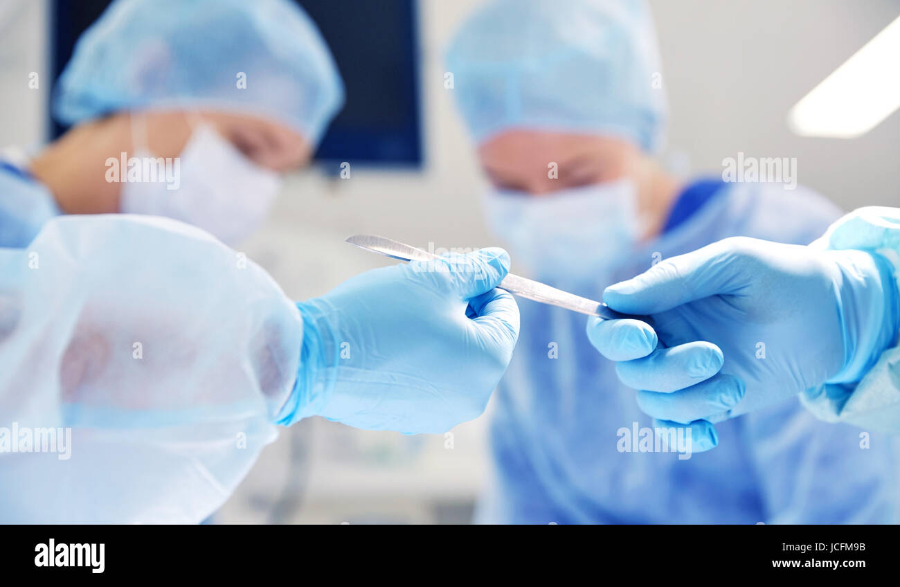 close up of hands with scalpel at operation Stock Photo