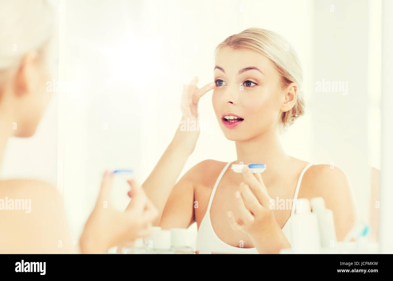 young woman putting on contact lenses at bathroom Stock Photo Alamy