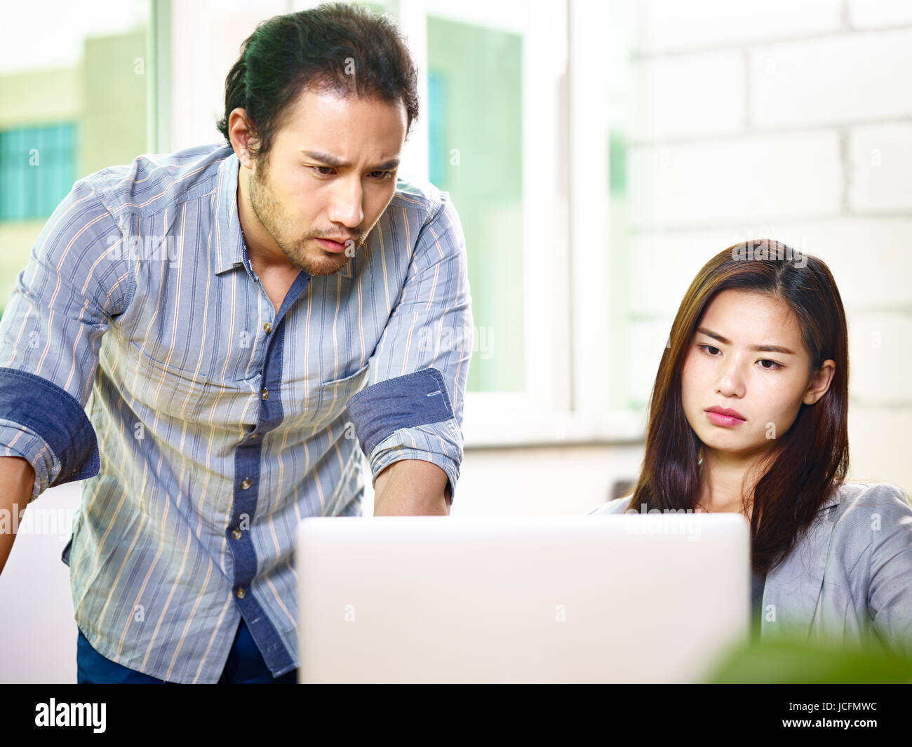 asian business coworkers looking at screen of laptop with frustration. Stock Photo
