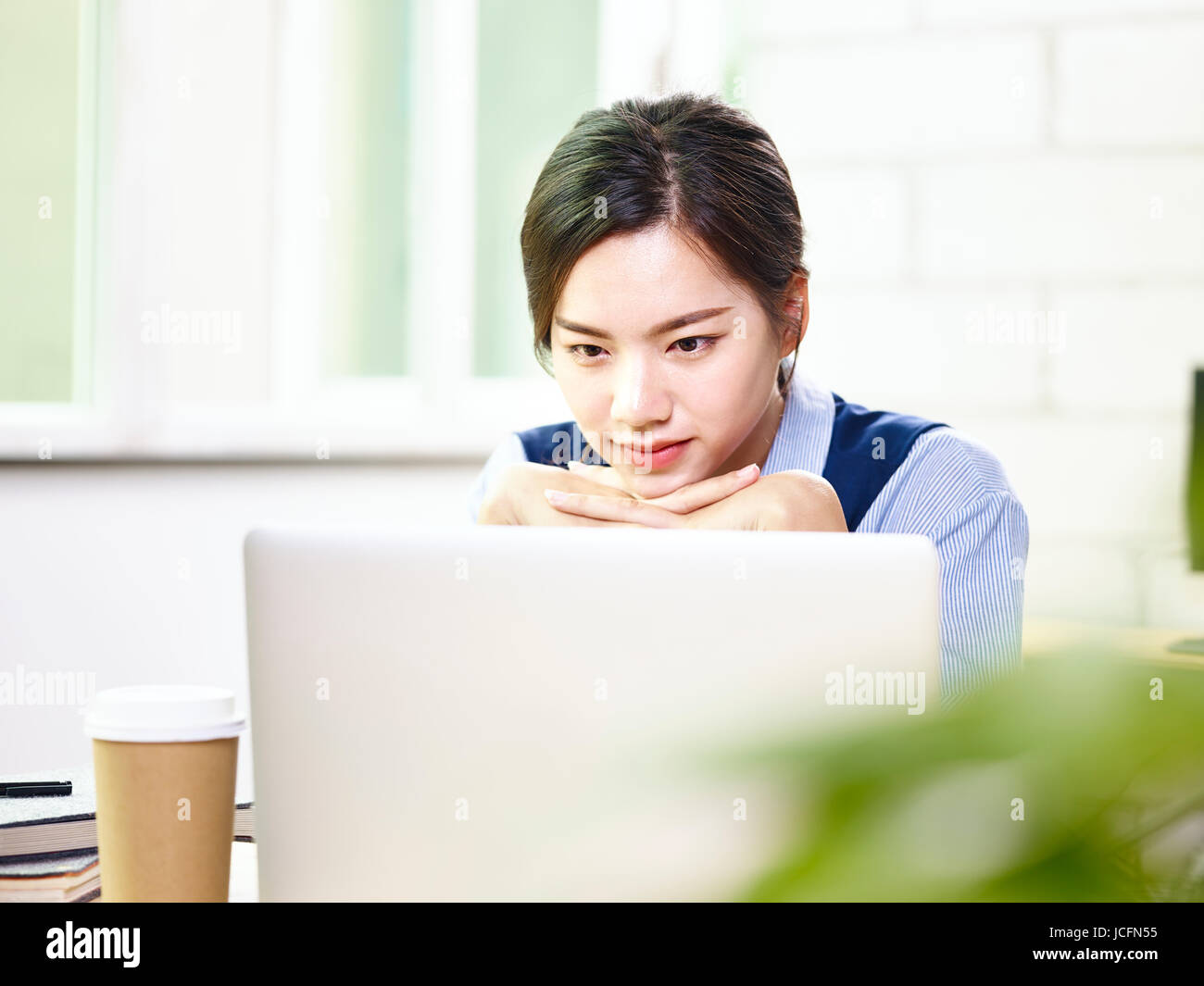 young asian businesswoman looking at laptop computer thinking in office. Stock Photo