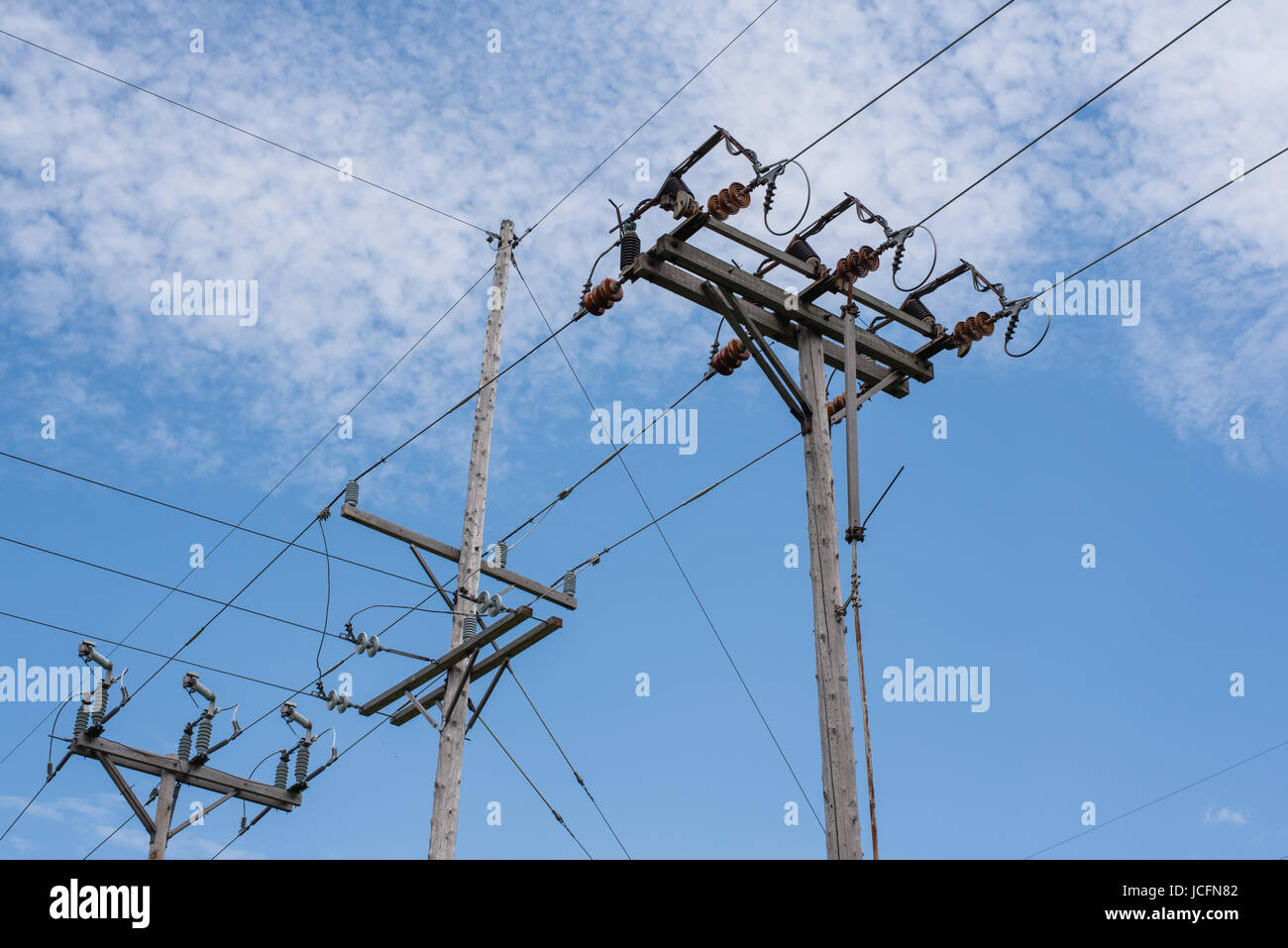 Power poles and lines under a cloudy, blue sky Stock Photo - Alamy
